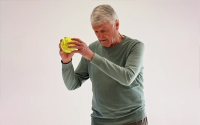 exercices double tâche seniors, ici un homme qui lance un ballon Brain Ball
