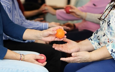 Atelier collectif avec des balles de rééducation et de stimulation sensorielle, illustrant la différence entre sport santé et APA dans la pratique adaptée aux besoins des participants.