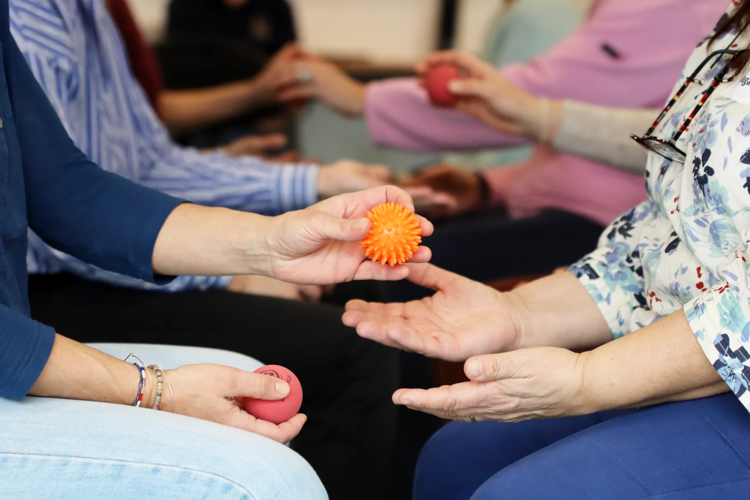 Atelier collectif avec des balles de rééducation et de stimulation sensorielle, illustrant la différence entre sport santé et APA dans la pratique adaptée aux besoins des participants.