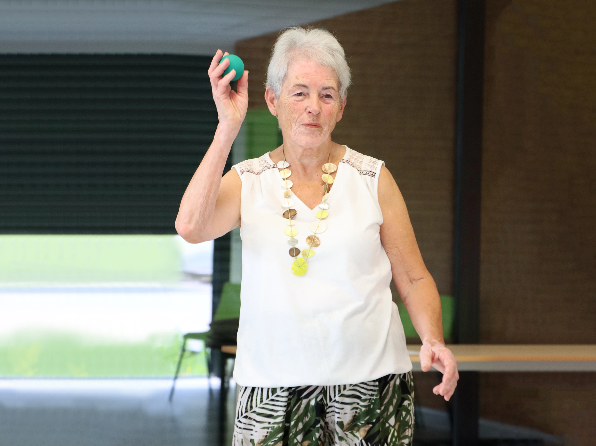 Femme senior en atelier Brain Ball® lançant une balle, illustrant le rôle des bras dans la prévention des chutes et l’amélioration de l’équilibre.