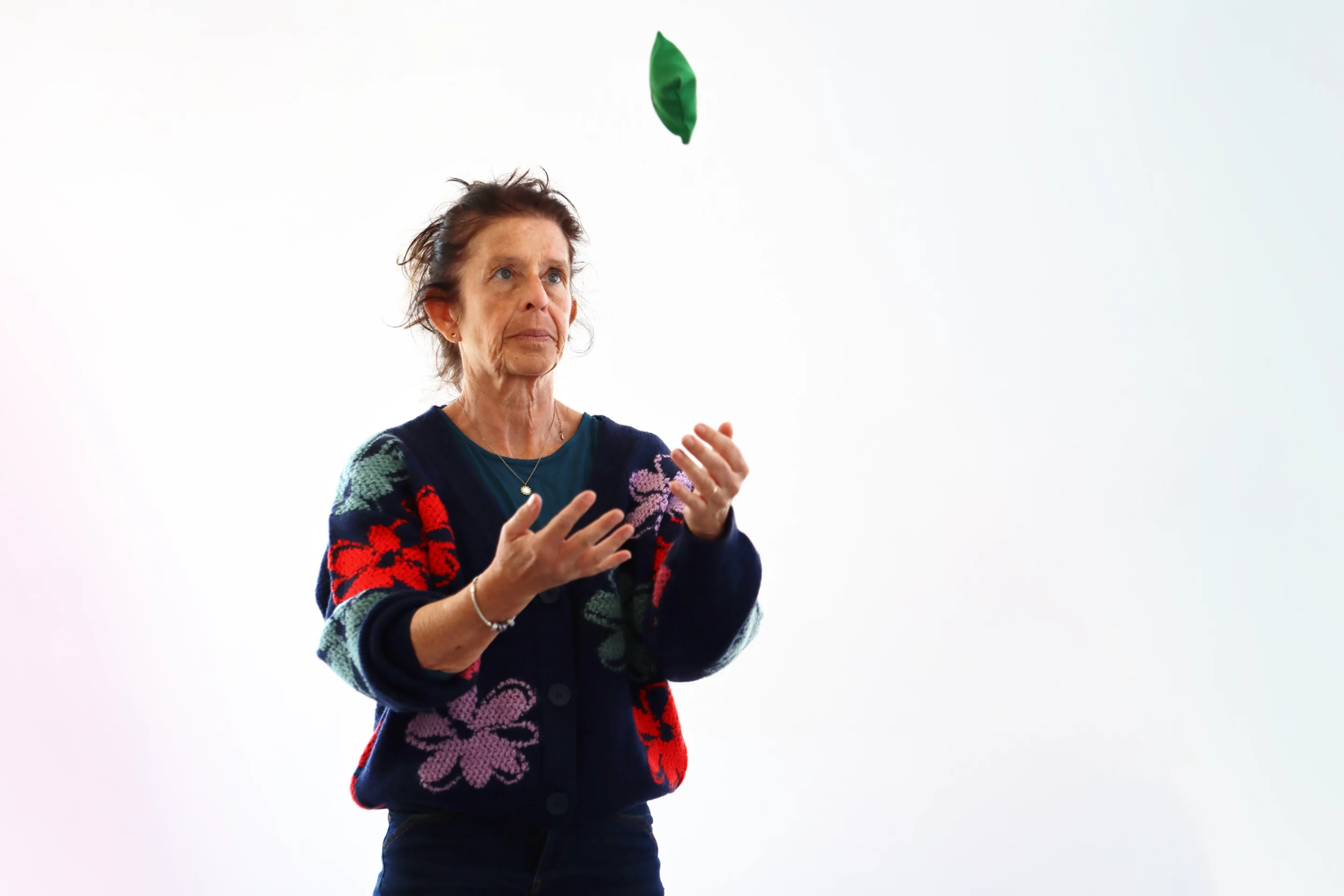 Femme senior en séance de rééducation orthoptique et activité motrice, lançant un sac de jonglage vert pour travailler coordination œil-main et équilibre.