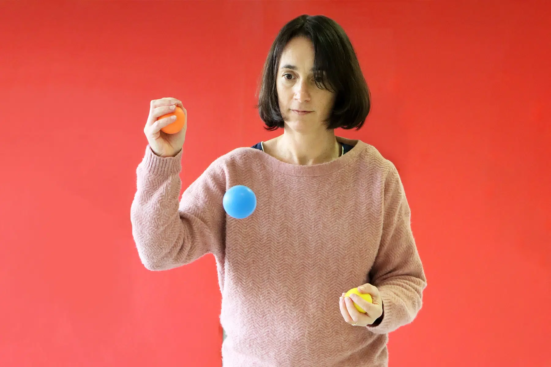 Femme réalisant un exercice Brain Ball® avec trois balles, illustrant la coordination œil-main et le suivi visuel du geste.
