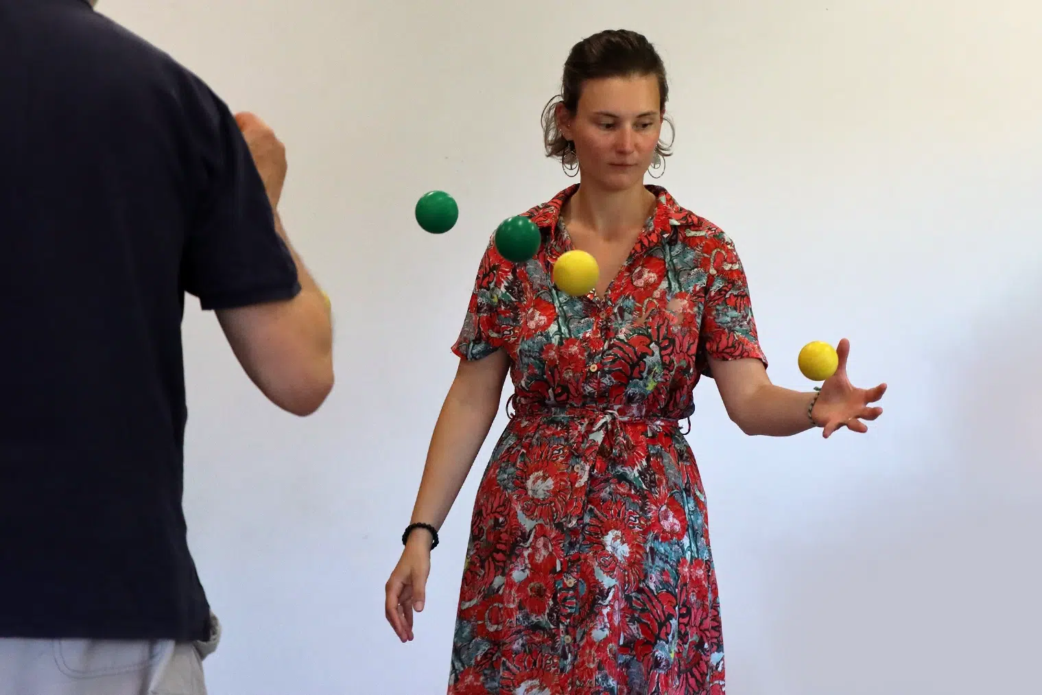Participante jonglant avec des balles vertes et jaunes lors d'un atelier Brain Ball®, illustrant le lien entre rythme, mouvement et cerveau.