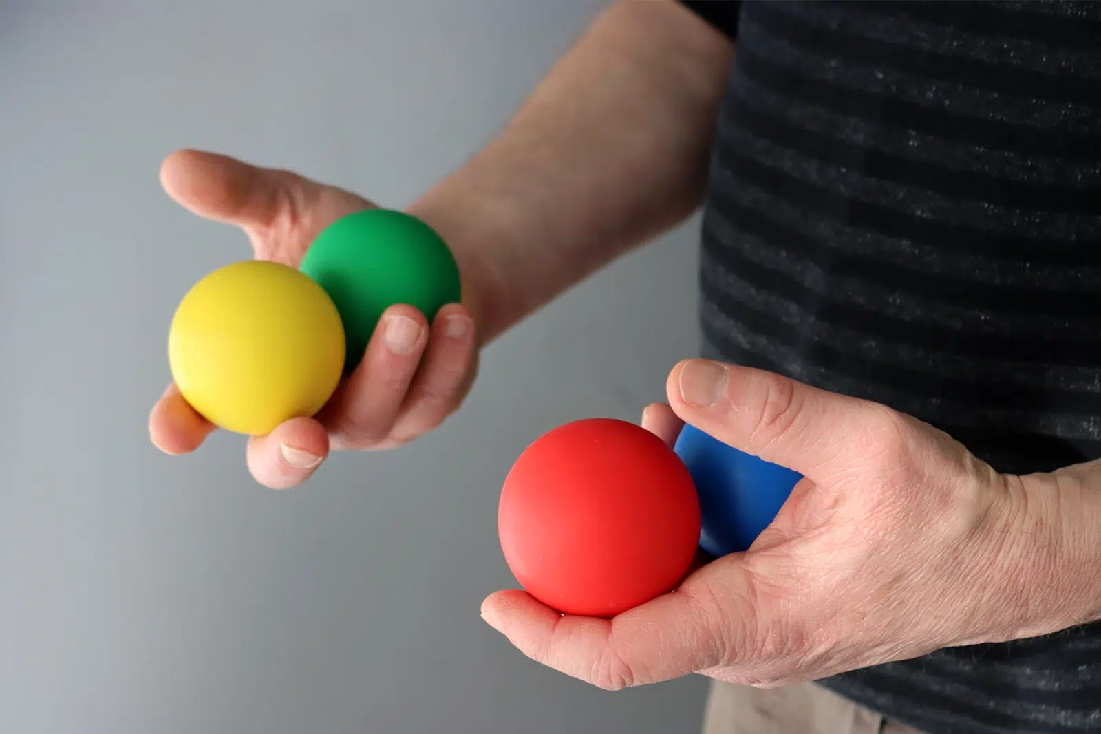 Mains tenant des balles de rebond colorées Brain Ball® — entraînement rythmique et performances attentionnelles dans le TDAH